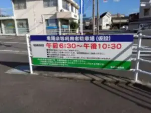 alt="踏切を渡った先に10台ほどの駐車場がある「亀陽泉」"