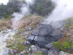 alt="小松地獄の岩場の隙間から立ち上がる噴気ガス"
